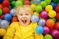 Happy little boy having fun in ball pit with colorful balls. Child playing on indoor playground Royalty Free Stock Photo