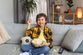 Happy little boy having fun, watching football on tv and eating popcorn, sitting on messy sofa and laughing, free space Royalty Free Stock Photo