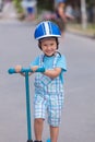 Happy little boy with helmet, playing with his scooter outdoor Royalty Free Stock Photo