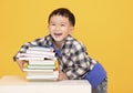 Happy little boy holding large books isolated on yellow background Royalty Free Stock Photo