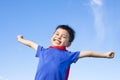 Happy little boy imitate superhero and open arms with blue sky