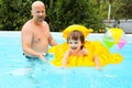 Happy little boy on inflatable toy swimms with his father in poo