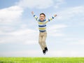 Happy little boy jumping over blue sky and grass Royalty Free Stock Photo