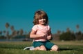 Happy little boy lying on the grass at the spring day. Portrait of a smiling child lying on green grass in park.