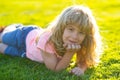 Happy little boy lying on the grass at the spring day. Portrait of a smiling child lying on green grass in park. Cute Royalty Free Stock Photo