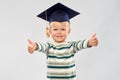 Happy little boy in mortar board showing thumbs up Royalty Free Stock Photo