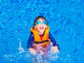 Happy little boy with orange life jacket has fun and enjoy in the swimming pool Royalty Free Stock Photo