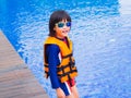 Happy little boy thumbs up with orange life jacket has fun and enjoy in the swimming pool Royalty Free Stock Photo