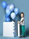 Happy little boy with pastel color blue balloons and empty white box for birthday party Royalty Free Stock Photo