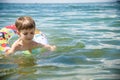 Happy little boy playing with colorful inflatable ring in outdoor swimming sear river lake or pool on hot summer day. Kids learn Royalty Free Stock Photo