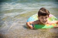 Happy little boy playing with colorful inflatable ring in outdoor swimming sear river lake or pool on hot summer day. Kids learn Royalty Free Stock Photo