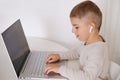 Happy little boy playing game on laptop at home. Portrait of a child at home watching cartoon on the computer. Modern Royalty Free Stock Photo