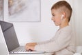 Happy little boy playing game on laptop at home. Portrait of a child at home watching cartoon on the computer. Modern Royalty Free Stock Photo