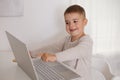 Happy little boy playing game on laptop at home. Portrait of a child at home watching cartoon on the computer. Modern Royalty Free Stock Photo