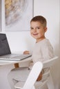 Happy little boy playing game on laptop at home. Portrait of a child at home watching cartoon on the computer. Modern Royalty Free Stock Photo