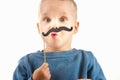 Happy little boy playing with a paper mustache, laughing while d Royalty Free Stock Photo