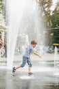 Happy little boy playing in square between jets of water in dry fountain on summer day. Having fun Royalty Free Stock Photo