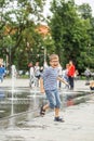 Happy little boy playing in square between jets of water in dry fountain on summer day. Having fun Royalty Free Stock Photo