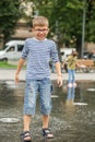 Happy little boy playing in square between jets of water in dry fountain on summer day. Having fun Royalty Free Stock Photo