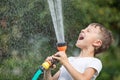 Happy little boy pouring water from a hose. Royalty Free Stock Photo