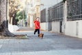 Happy little boy running with his dachshund dog on a city sidewalk Royalty Free Stock Photo