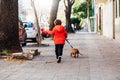 Happy little boy running with his dachshund dog on a city sidewalk. View of backs. Royalty Free Stock Photo