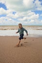 Happy little boy running at the sea coast Royalty Free Stock Photo
