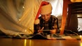 Happy little boy in Santa hat lying in DIY kid's tent using smartphone.