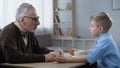 Happy little boy sharing news with grandfather, trustful family relations