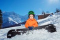 Happy little boy sit with snowboard on alpine ski track Royalty Free Stock Photo