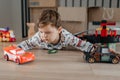 Happy little boy sitting on white carpet at home and playing with car toy Royalty Free Stock Photo