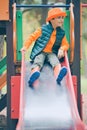 Happy little boy slides down the slide at the children& x27;s playground Royalty Free Stock Photo