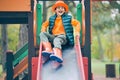 Happy little boy slides down the slide at the children& x27;s playground Royalty Free Stock Photo