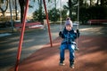 Happy little boy on swing in beautiful winter day have fun and makes faces Royalty Free Stock Photo