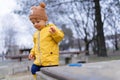 Happy little boy with teddy bear cap playing on playground at sandpit during autumn day.