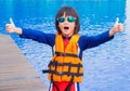 Happy little boy thumbs up with orange life jacket has fun and enjoy in the swimming pool Royalty Free Stock Photo