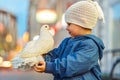 Happy little boy with white pigeon sitting on arm in city