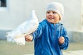 Happy little boy with white pigeon sitting on arm in city