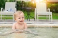 Happy little caucasian blond toddler boy swimming in wading pool on bright summer day at resort. Adorable baby enjoying outdoor Royalty Free Stock Photo