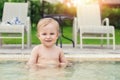 Happy little caucasian blond toddler boy swimming in wading pool on bright summer day at resort. Adorable baby enjoying Royalty Free Stock Photo