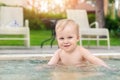 Happy little caucasian blond toddler boy swimming in wading pool on bright summer day at resort. Adorable baby enjoying Royalty Free Stock Photo