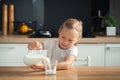 Happy little caucasian girl pouring milk in the glass in the stylish kitchen Royalty Free Stock Photo