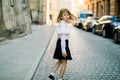 Happy little child, adorable blonde girl in black and white business wear, walking on old city street in ancient