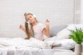Little girl listening to the music with the headphones on bed. Royalty Free Stock Photo