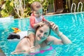 A happy little child in a bathing suit sits on the shoulders of the mother and plays with the hair on her head, pulls the hair. Royalty Free Stock Photo