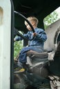 Happy little child boy playing inside old vintage truck car, holding big wheel. Slow life in countryside. Happy childhood concept Royalty Free Stock Photo