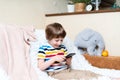 Happy little child boy playing online game, watching video on cellphone, sitting on couch entertaining in living room. Smiling Royalty Free Stock Photo