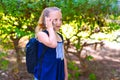 Happy little child girl go to school and talking on mobile phone at city park. Royalty Free Stock Photo