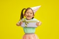 Happy Little Child Girl with Birthday Gift Box on Sunny Yellow Background, Isolated Portrait Royalty Free Stock Photo