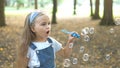 Happy little child girl blowing soap bubbles outside in green park. Outdoor summer activities for children concept Royalty Free Stock Photo